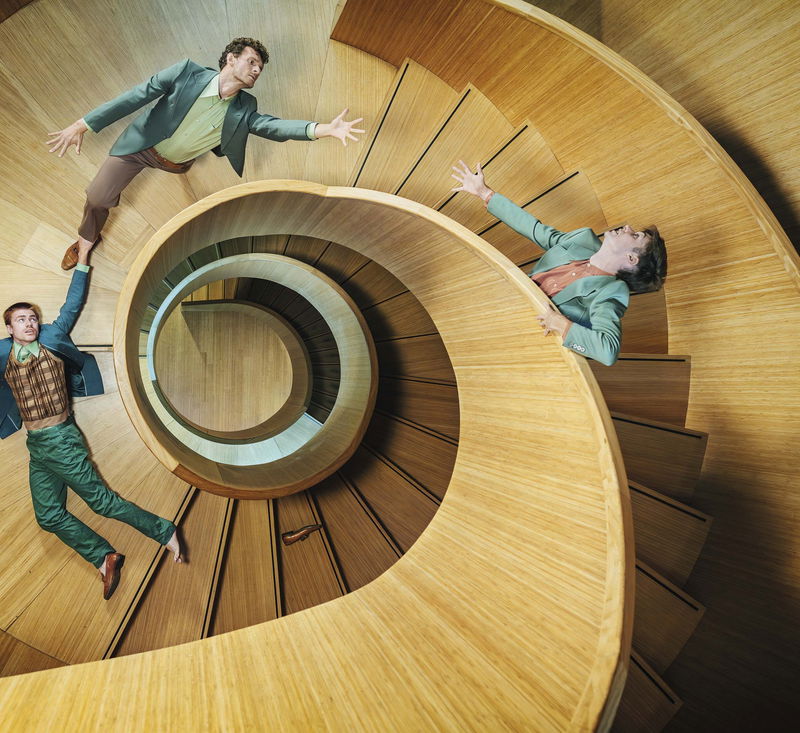 drie mannen proberen elkaar vast te pakken op een houten cirkel trap