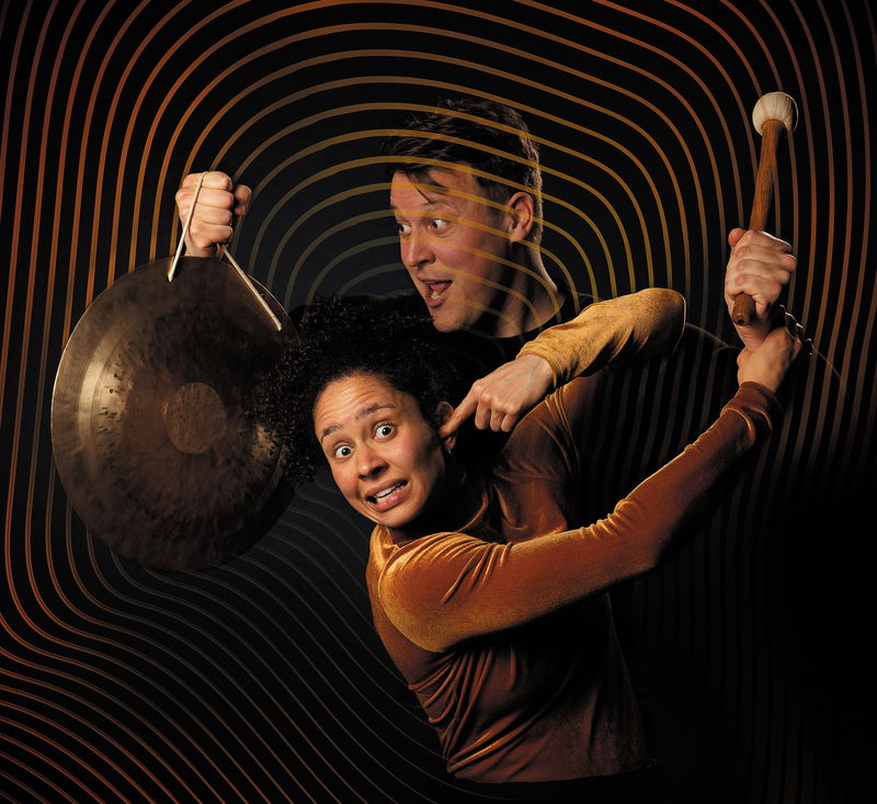 man en vrouw met een gong in hun hand terwijl ze ernaar wijzen en kijken